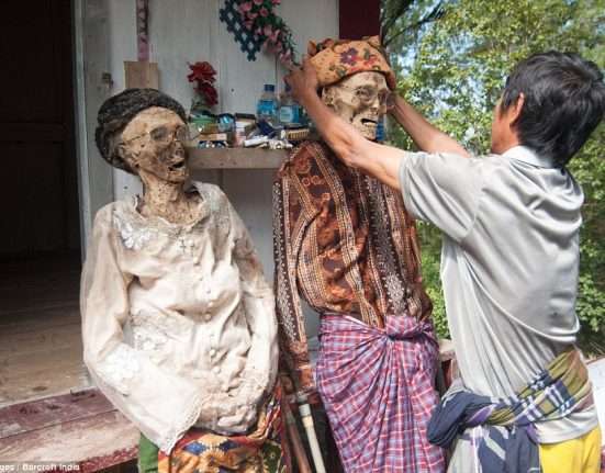 Indonesian peasants scrub corpses as part of an afterlife rite before dressing the deceased